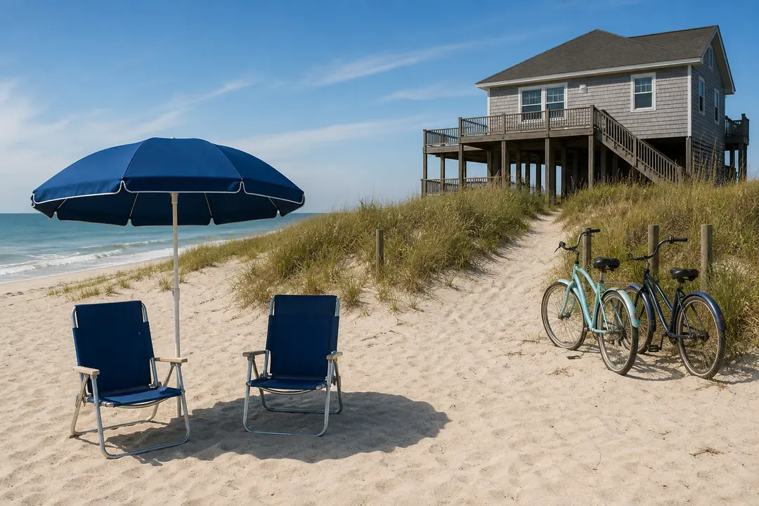 Two beach chairs, an umbrella, and two cruiser bikes stand beside a coastal vacation rental.