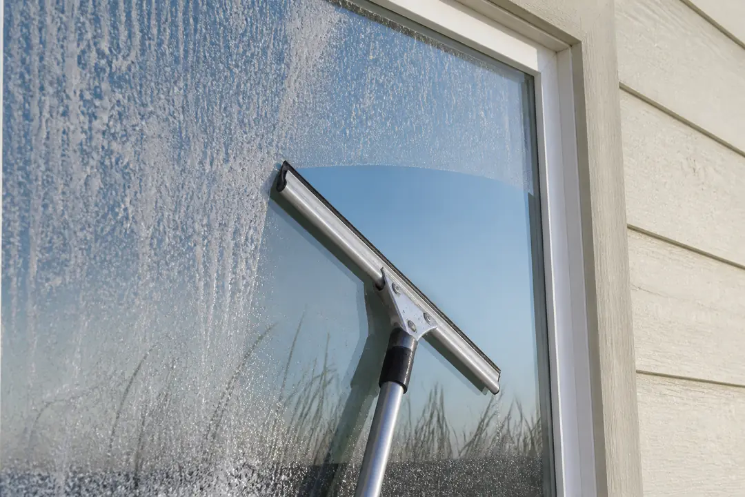 A squeegee clears salt spray from a window on a coastal Surfside Beach home.